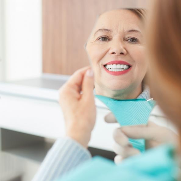 Woman looking at smile after same day dental crown restoration