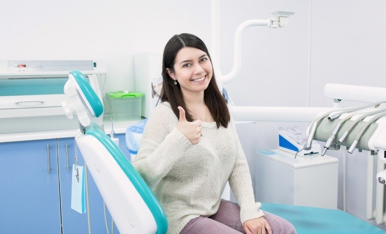 Smiling woman giving thumbs up after CEREC dental restoration