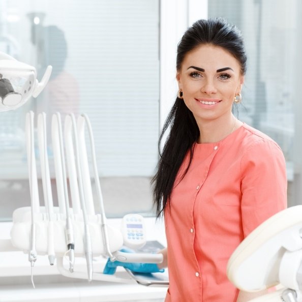 Dental team member smiling after providing tooth colored fillings