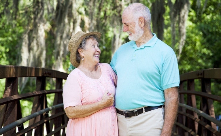 Older man and woman enjoying the benefits of dental implant supported dentures