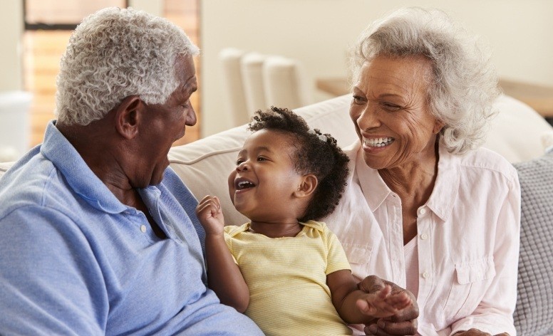 Older couple smiling at grandchild and enjoying the benefits of dental implants