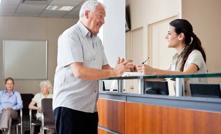 Man discussing tooth replacement with dental implants with dentistry team member