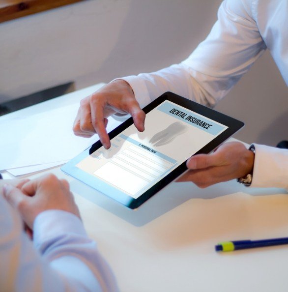 Dentist and patient reviewing dental insurance forms on tablet computer