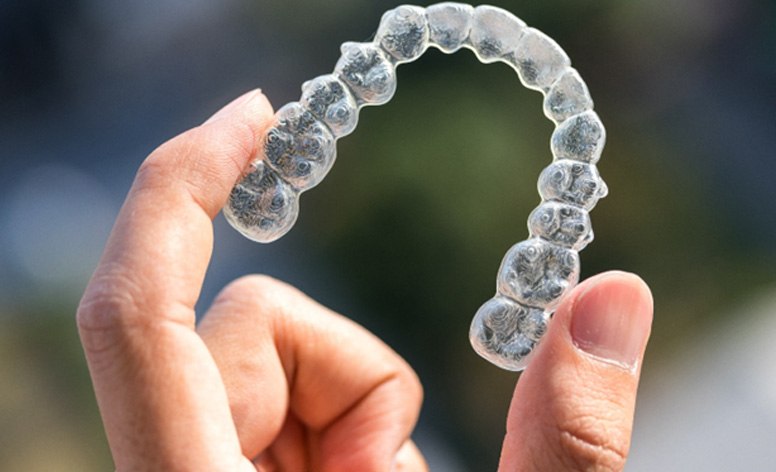 closeup of person holding Invisalign aligner 