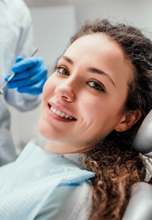 patient smiling while sitting in dental chair 