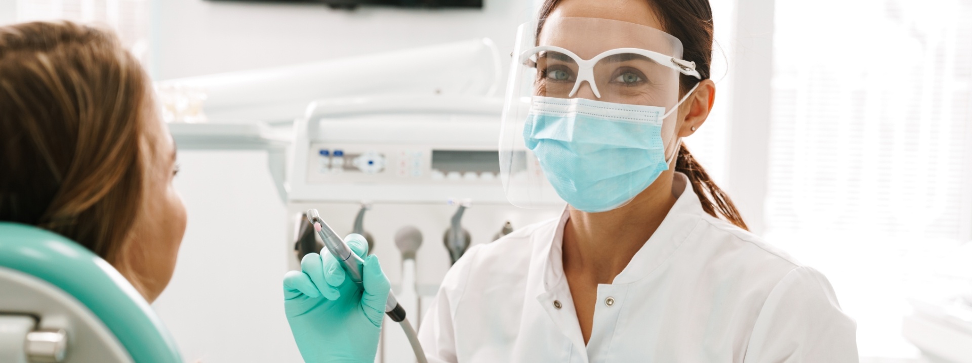 dental employee holding tool with patient in chair