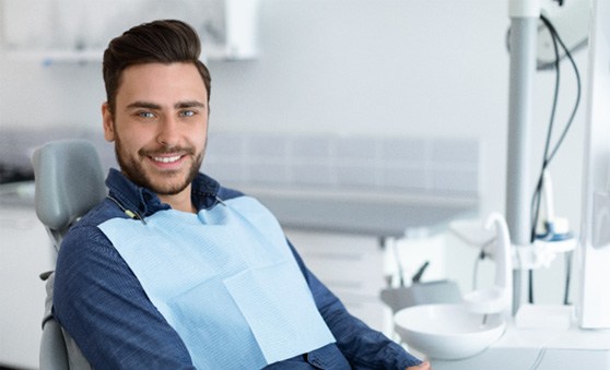 Man sitting in dental chair with hands folded