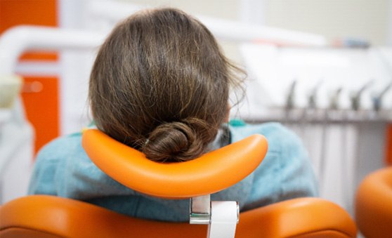 Woman leaning back in an orange dental chair