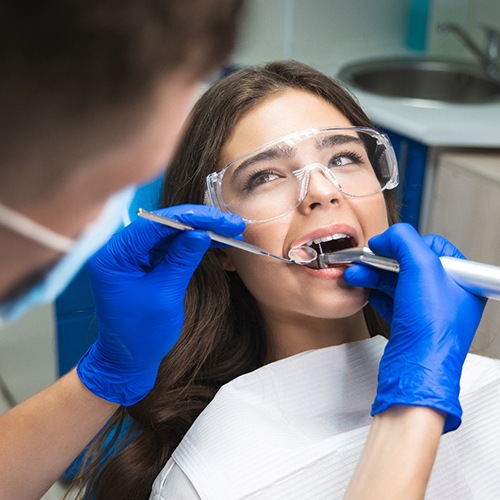 Woman with dark hair and protective goggles undergoing root canal