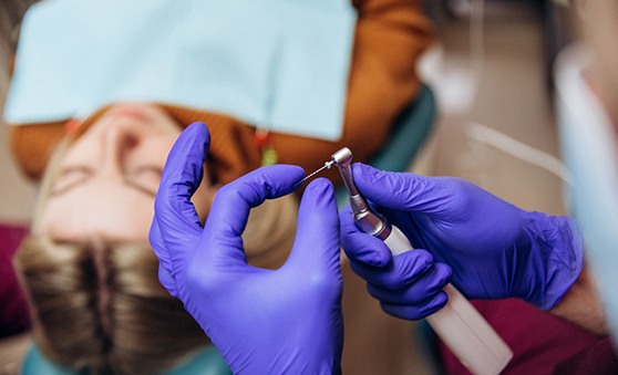 Gloved hands of dentist preparing instrument for patient’s root canal