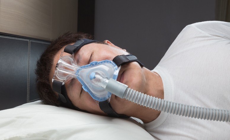 Man with CPAP sleep apnea therapy device sleeping soundly