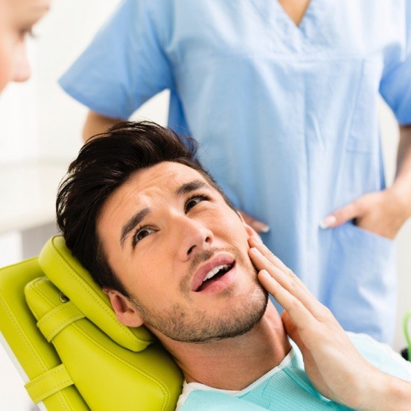 Man in need of T M J therapy holding jaw in pain