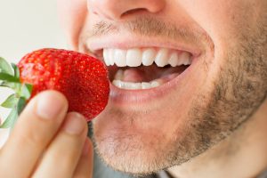 man eating strawberry white teeth