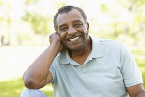 older man smiling with nice teeth after receiving dental implants