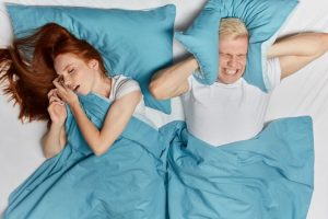 young man upset about woman snoring loudly from sleep apnea