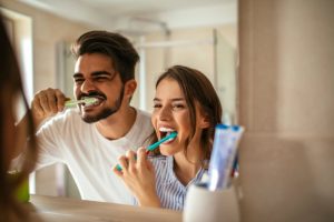 Family smiling while brushing their teeth with toothbrushes from the dentist