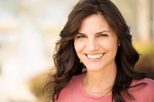 Woman smiling outside after visiting her cosmetic dentist