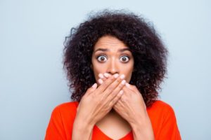 woman with cracked teeth covering her mouth with her hands