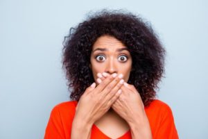 woman with cracked teeth covering her mouth with her hands 