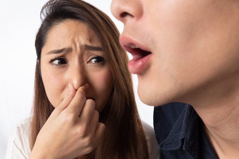 young woman covering nose because of bad breath