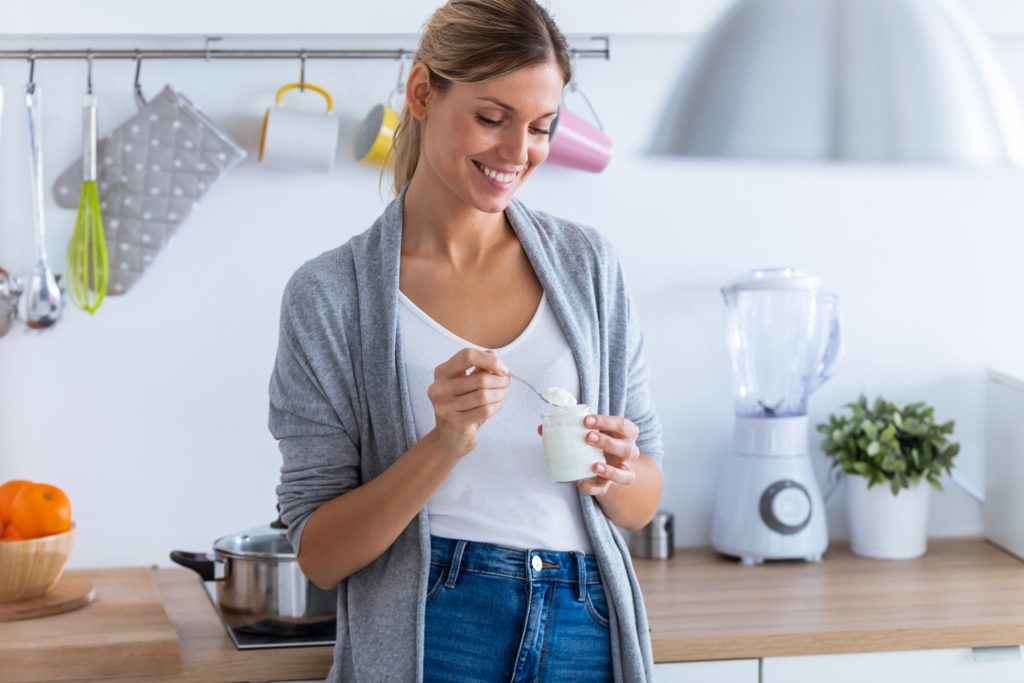 Woman smiling while eating yogurt at home