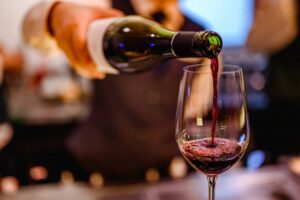 Person pouring a glass of red wine