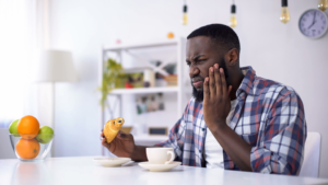 a man eating a pastry and dealing with a toothache